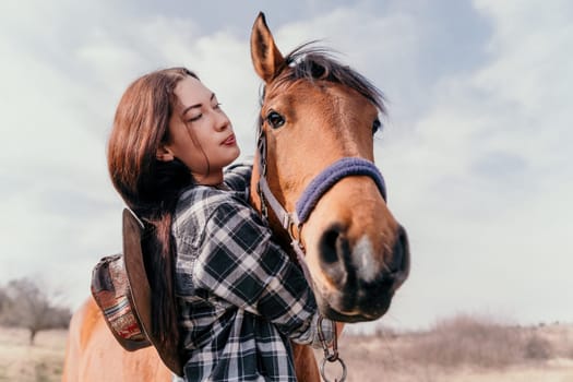 Cute happy young woman with horse. Rider female drives her horse in nature on evening sunset light background. Concept of outdoor riding, sports and recreation.