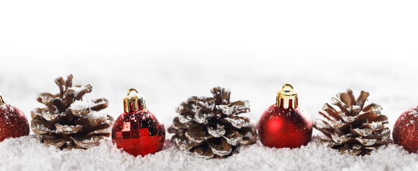 Red christmas balls and pine cones isolated on snow, Christmas banner