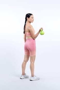 Vigorous energetic woman doing kettlebell weight lifting exercise on isolated background. Young athletic asian woman strength and endurance training session as body workout routine.