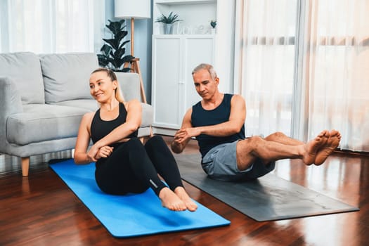 Athletic and sporty senior couple engaging matt exercising and doing crunch together at home exercise as concept of healthy fit body lifestyle after retirement. Clout