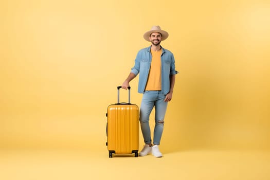 young adult Caucasian male in casual jean clothes with suitcase on yellow background. Neural network generated image. Not based on any actual person or scene.