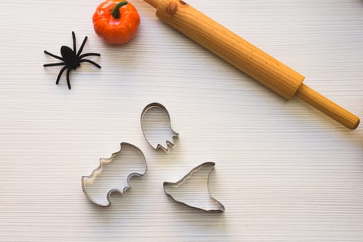 Making cookies for Halloween. A woman cuts out cookies from the dough in the form of pumpkin, cat, Ghost and bat.