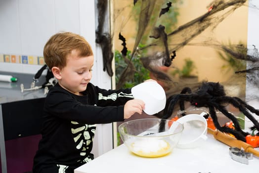 boy dressed as a skeleton preparing halloween cookies.Happy boy preparing for halloween. Festival in the kitchen..