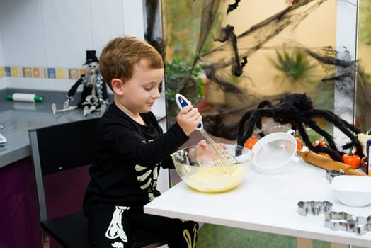 boy dressed as a skeleton preparing halloween cookies.Happy boy preparing for halloween. Festival in the kitchen..