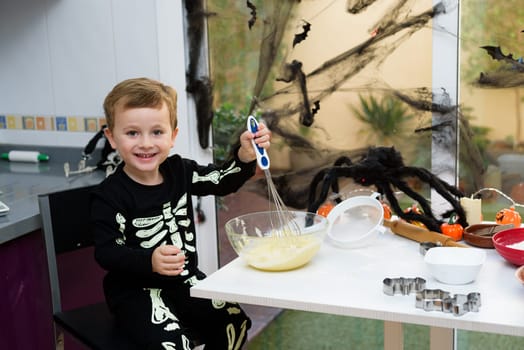 boy dressed as a skeleton preparing halloween cookies.Happy boy preparing for halloween. Festival in the kitchen..