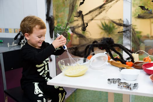 boy dressed as a skeleton preparing halloween cookies.Happy boy preparing for halloween. Festival in the kitchen..