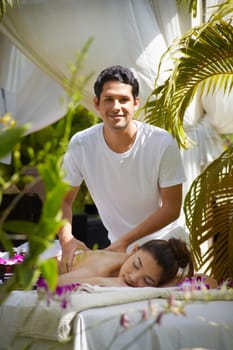 Portrait of masseur massaging young beautiful asian woman during beauty treatment in exclusive resort. Vertical shape, front view.