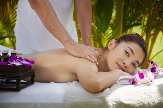 Young beautiful asian woman gets massage and beauty treatment in luxury resort. Side view