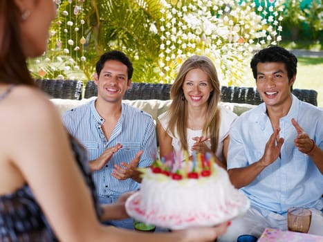 Birthday party with cake, drinks and happy caucasian and asian friends clapping hands. Front view