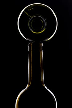 green wine bottles shiny on top of each other against black background