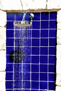 outdoor shower with water behind a swimming pool
