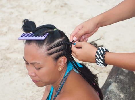asian woman gets a hair braiding on the beach