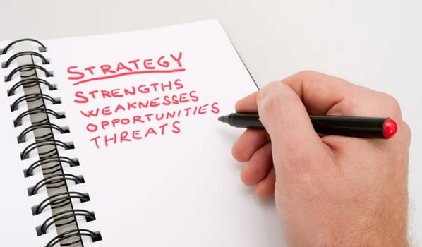 SWOT Analysis - Close up of Hand With Red Marker and Open Notebook