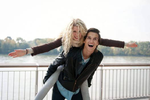 Young couple enjoying life together outdoor - man holding woman who pretends to fly