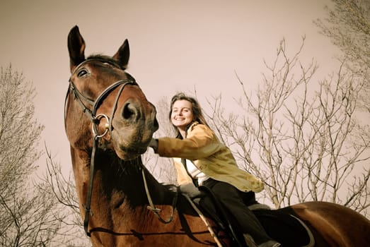 Young woman riding on big brown horse