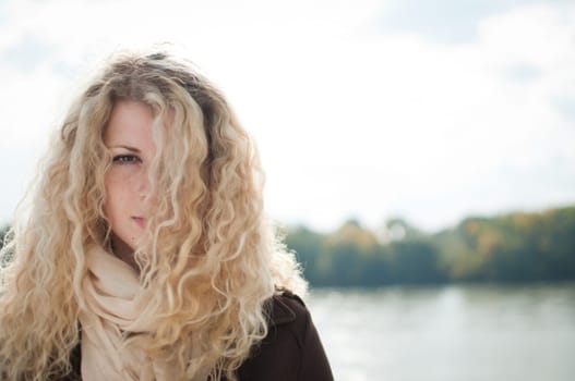 Portrait of young woman with blond hair covering one eye outdoor with copy space