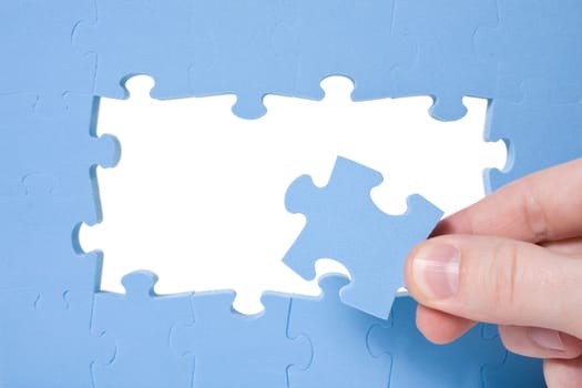 Hand collecting a part of a blue puzzle