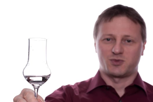 A smiling man toasts with a glass of schnapps