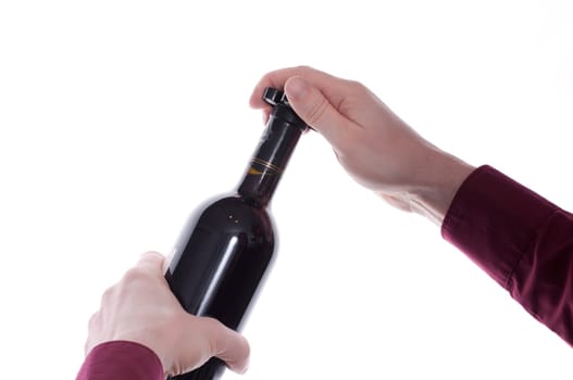 Two hands remove the capsule of a wine bottle with a capsule knife