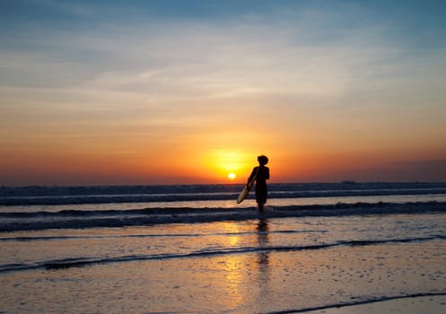 Surfer and waves at sunset in Bali, Indonesia