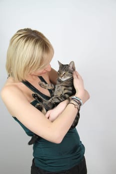 A gril holds a young cat in her hands