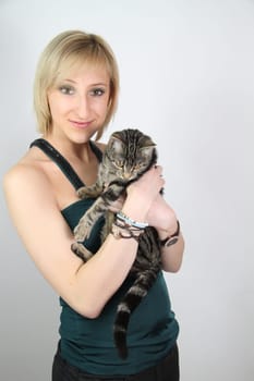 A gril holds a young cat in her hands