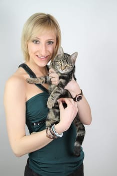 A gril holds a young cat in her hands