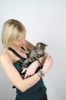 A gril holds a young cat in her hands