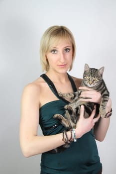 A gril holds a young cat in her hands