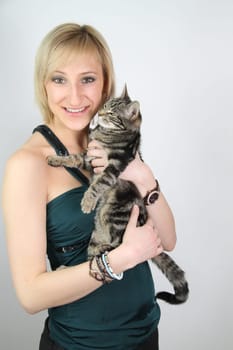 A gril holds a young cat in her hands