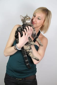 A gril holds a young cat in her hands