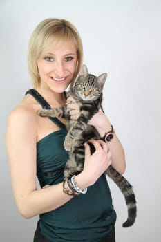 A gril holds a young cat in her hands