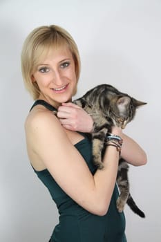 A gril holds a young cat in her hands