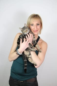 A gril holds a young cat in her hands