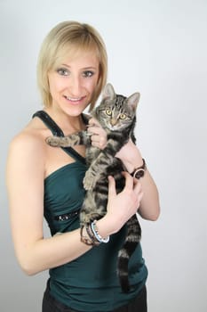 A gril holds a young cat in her hands