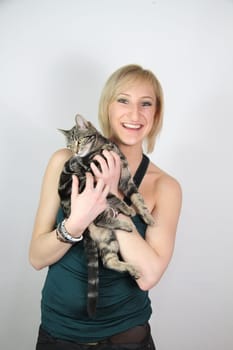 A gril holds a young cat in her hands