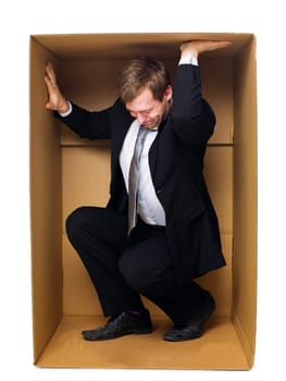 Well dressed businessman in a tight cardboard box isolated on white background
