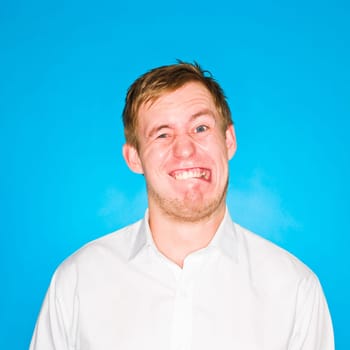 Young man making a funny face on blue background