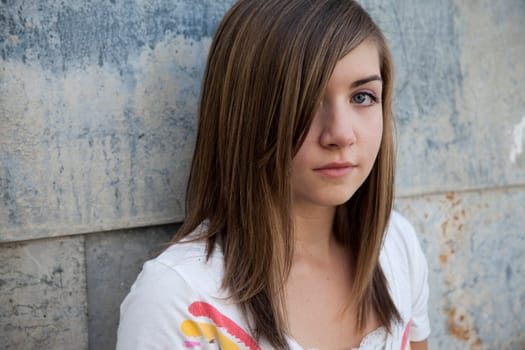 Teenage girl with somber expression against grunge wall