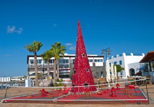 A Red Christmas Tree surrounded by presents and Red Lanterns in a town square