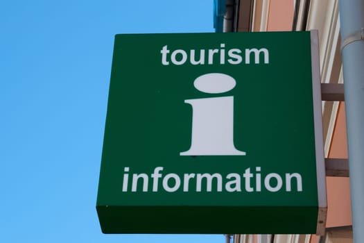A green wall sign with Tourism
