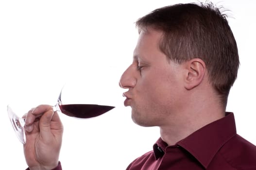 A man brings a glass of red wine to his mouth
