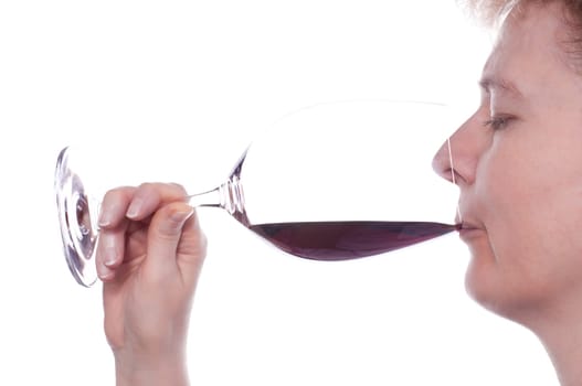 A blonde woman enjoys a red wine from a wine glass