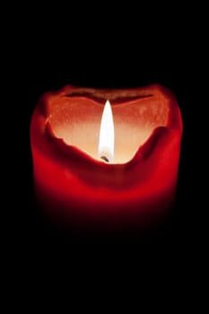 Candlelight,red candle with flame against black background