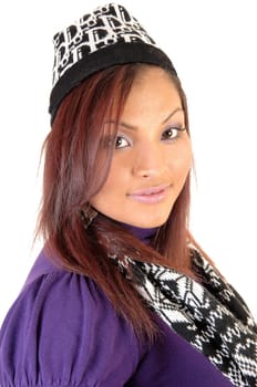 A closeup portrait on a pretty Hispanic woman in a knitted hat and scarf with her red hair looking into the camera.
