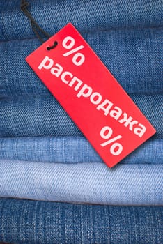Red Russian Sale Sign With Stack of Blue Jeans in Background