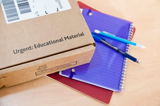 High angle shot of distance learning cardboard box with notebooks underneath.