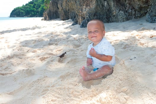 baby playing with sand on a tropical beach