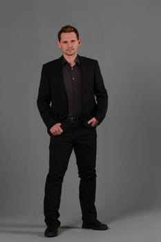 Business man in black suit on grey background in studio