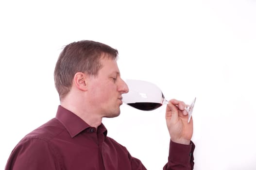 A man drinks a glass of red wine